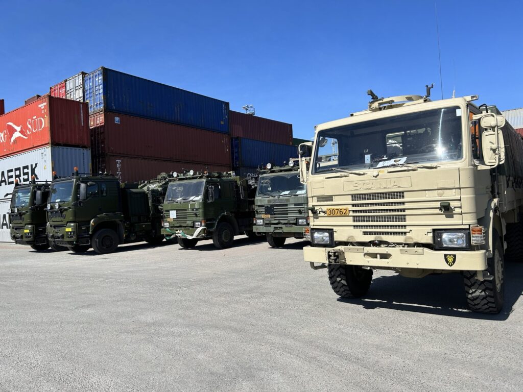 Militaere lastebiler i beige og mørkegrønn staar parkert