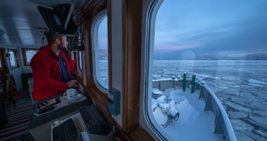 Skipper ser ut av vindet paa baaten sin.