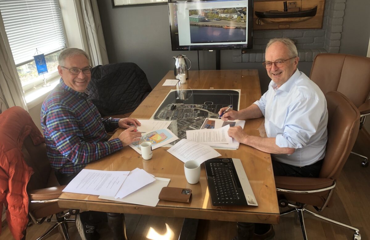 Gjermund Riise Brekke og Einar Olsen sitter overfor hverandre ved et bord og undertegner dokumenter paa hver sin side.