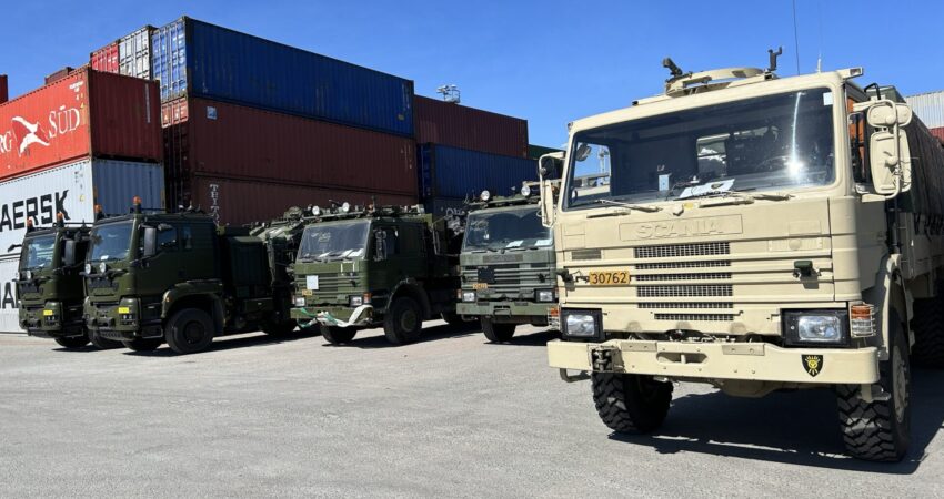 Militaere lastebiler i beige og mørkegrønn staar parkert