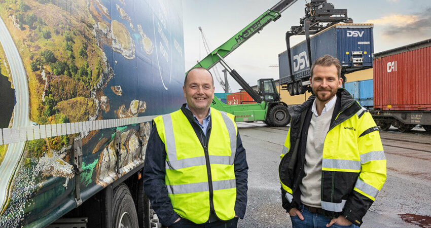 Jarle Heyerdahl og Bjørn Ottersen staar ved siden av hverandre med gul refleksvest. containere og biogassbilen